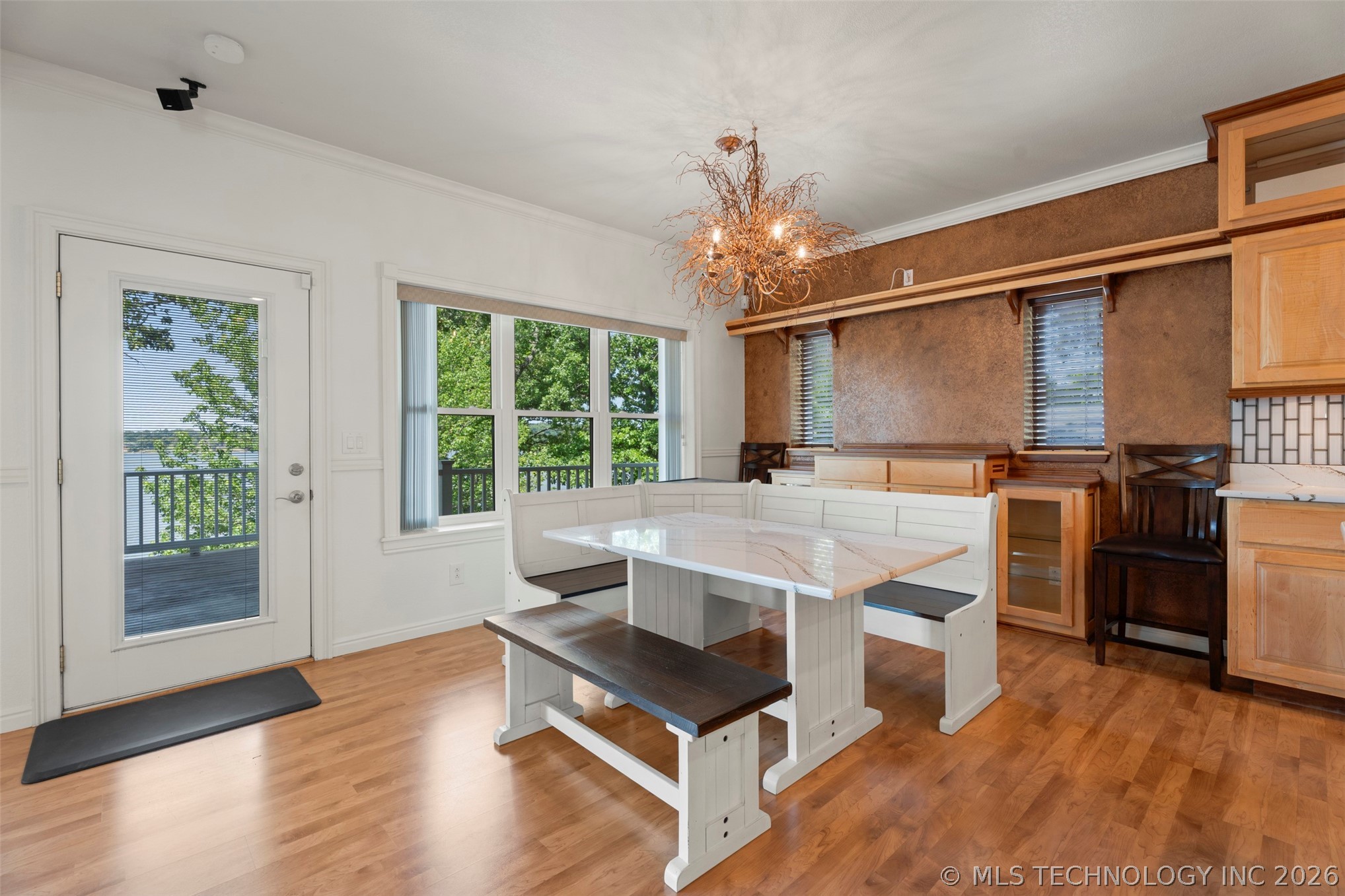 Dining nook with branch-style chandelier, custom built-in banquette seating, and a door opening to the upper deck and the lake