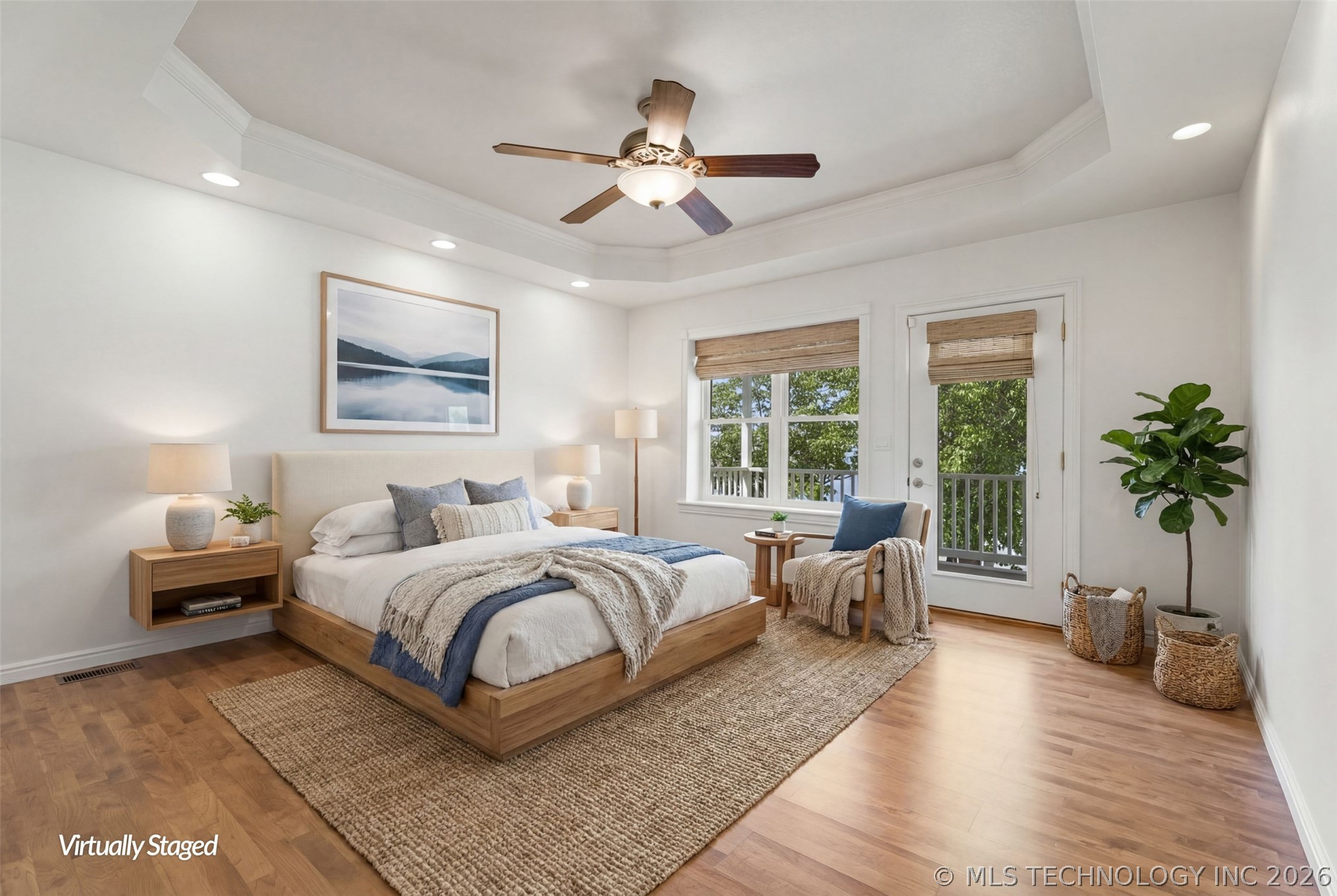 Primary bedroom with tray ceiling, hardwood floors, and a private door opening directly to the lake-view deck