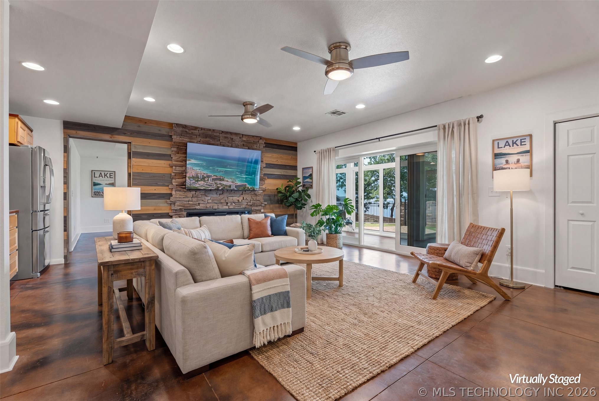 Open great room with sectional, woodland fireplace, sliders to the lake-view deck, and a second tray-ceiling living area beyond