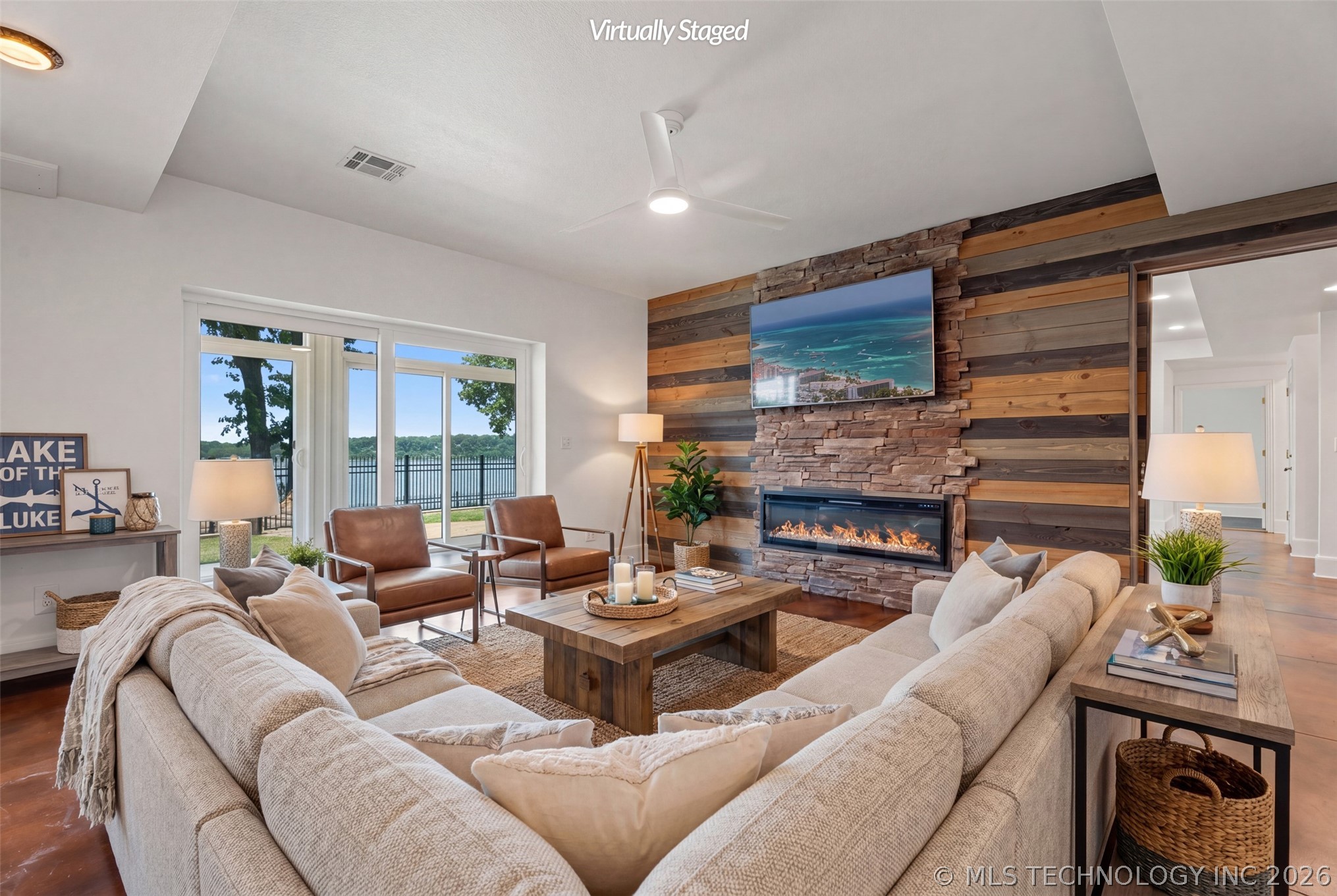 Second living area with linear gas fireplace, dark sectional, and sliders opening directly to a lake-view patio